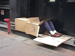 Photo of a homeless man sleeping in a box